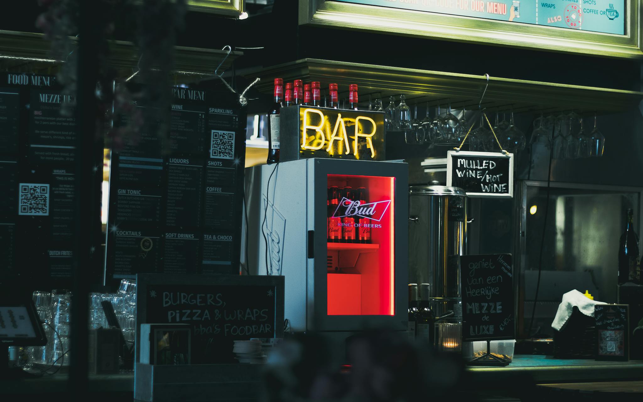 A cozy bar setup in Utrecht featuring neon signs, menus, and a distinct fridge.