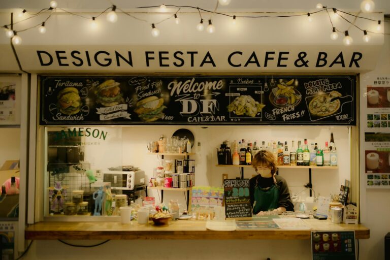 A welcoming view of the Design Festa Café & Bar with illuminated string lights and a friendly barista.